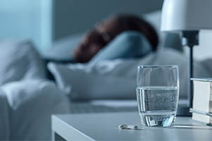 glass of water and pill on nightstand